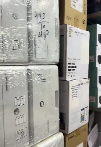 Wrapped, boxed HP printers stacked in the shop